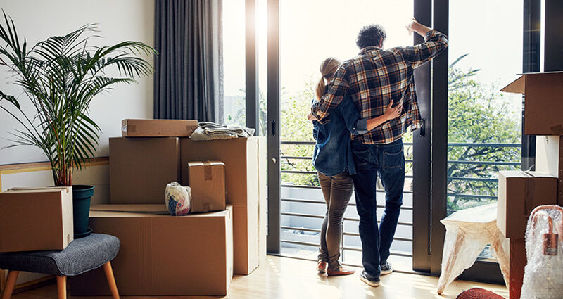 Couple looking out their balcony surrounded by moving boxes