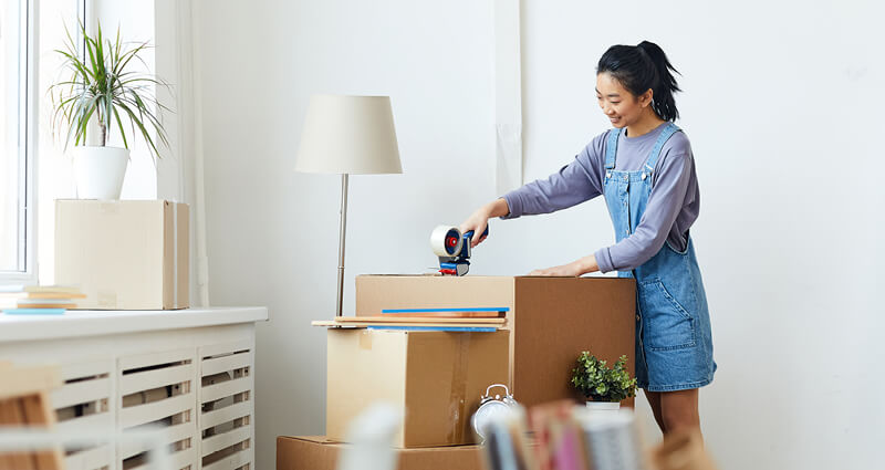 Young woman packing boxes for her new apartment