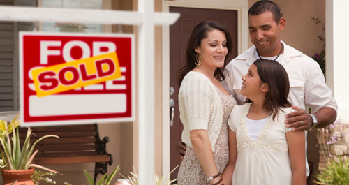 Family in front of new home sold sign