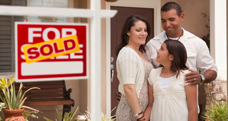 Family in front of new home sold sign