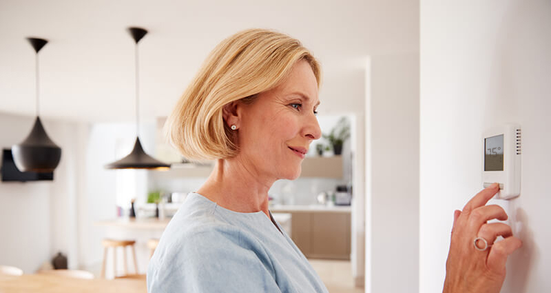 Woman sitting on couch pointing remote control at AC