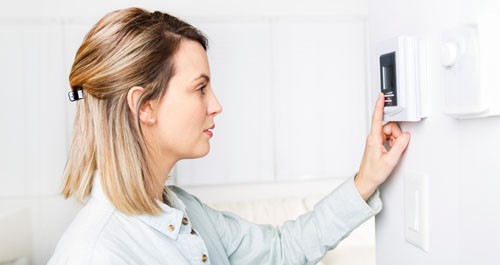 Woman setting thermostat at home