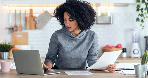 A woman reading her energy bill at a desk with a computer